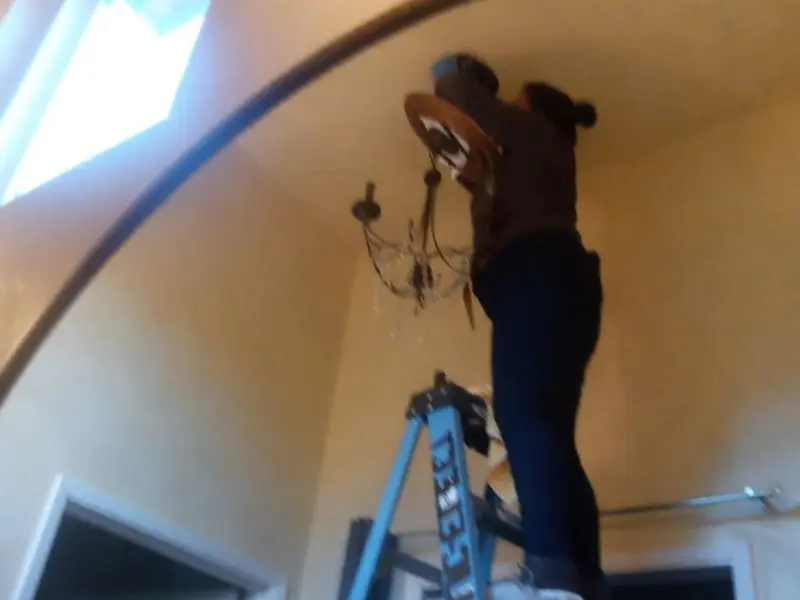 Electrician installing a chandelier in a Lansing residence